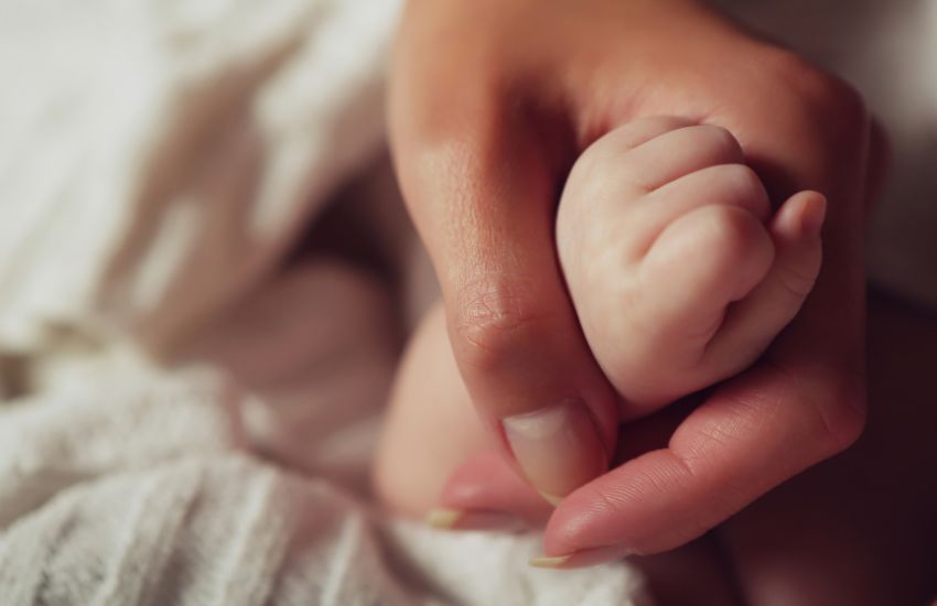 Mother holding newborn baby's hand