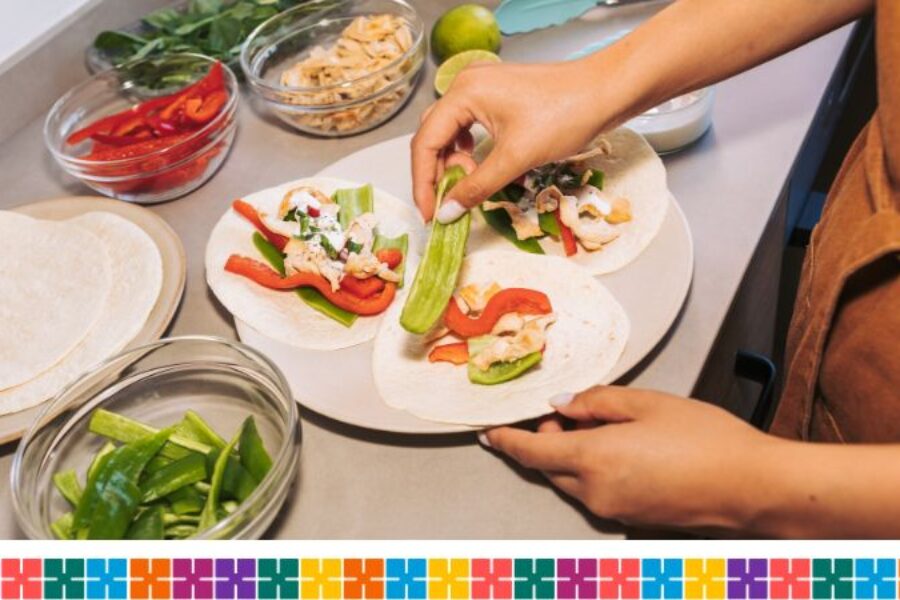 Someone is making tacos on a kitchen worktop with bowls of tortilla and vegetables laid out in different bowls.