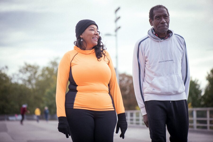 Older Black man and younger Black woman exercise outdoors