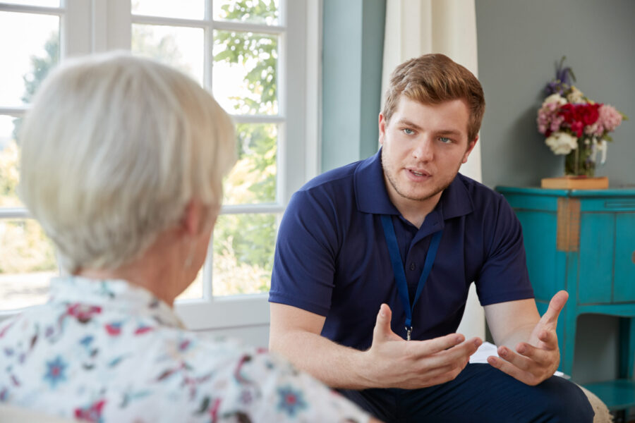 Male staff member talking to older woman in her home