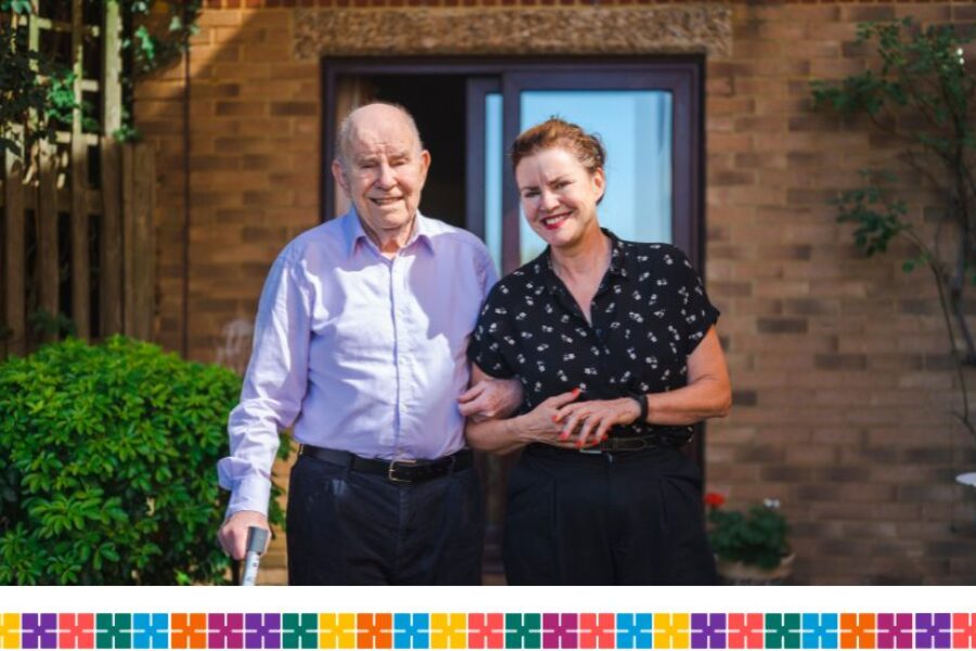 Older man and carer standing outside house