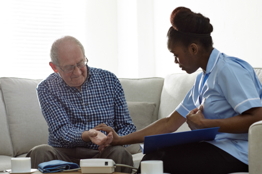 Young community nurse sitting with an elderly man