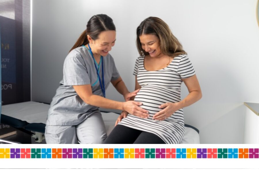 midwife checks pregnant woman, both smiling